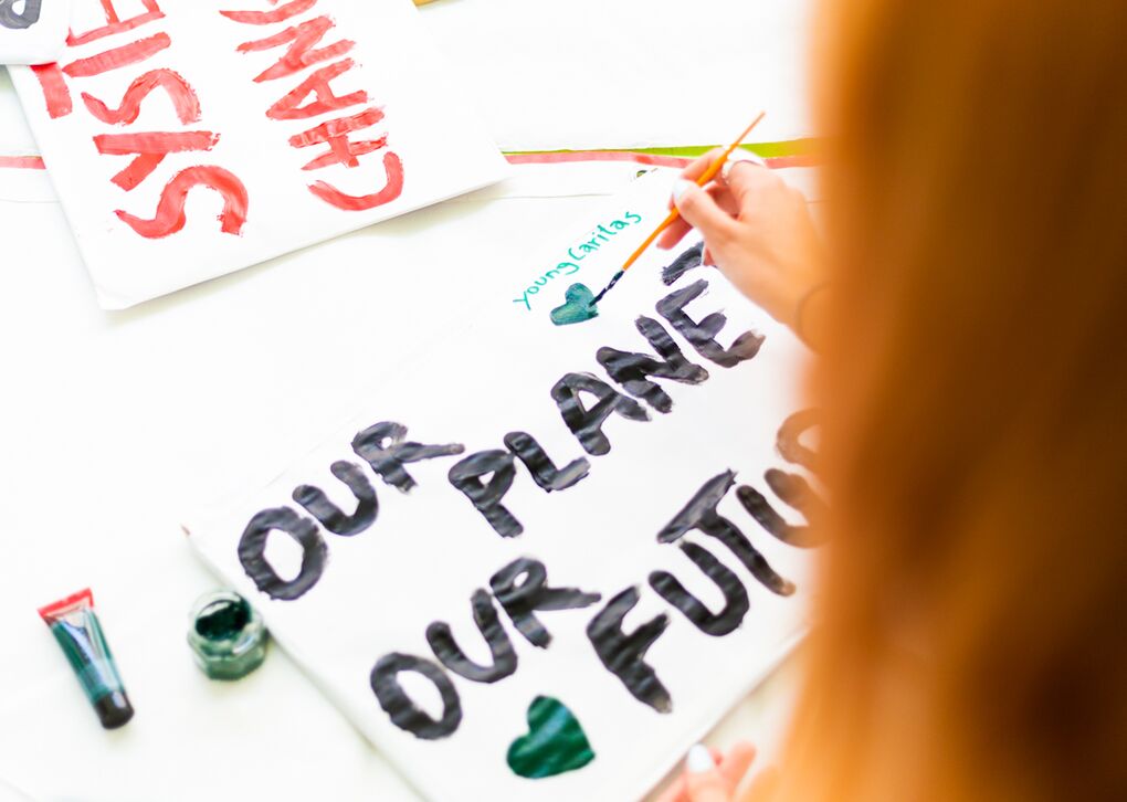 Junge Menschen malen auf Plakaten mit Botschaften über unseren Planeten und unsere Zukunft.