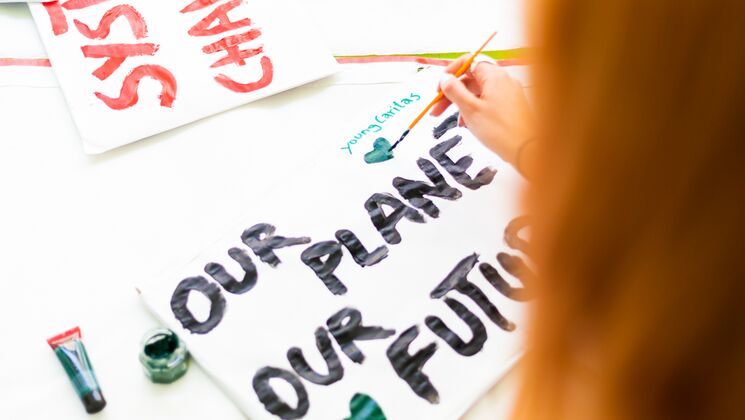 Junge Menschen malen auf Plakaten mit Botschaften über unseren Planeten und unsere Zukunft.